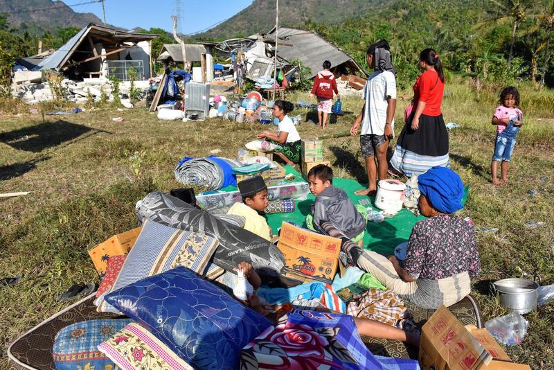 Residents sit outside their home with their belongings following a strong earthquake in Pemenang, North Lombok. Reuters