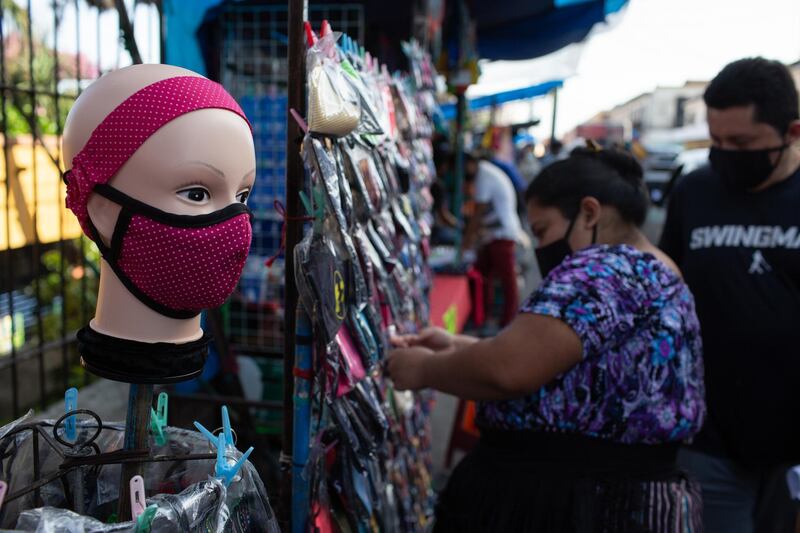 People wearing protective masks sell masks outside the Central Market in Guatemala City, Guatemala. Bloomberg
