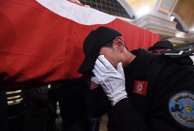 A Tunisian policeman mourns as he carries the coffin of a member of the presidential guards, who was killed in a suicide attack on a bus in central Tunis the previous day. Fethi Belaid/AFP Photo 

