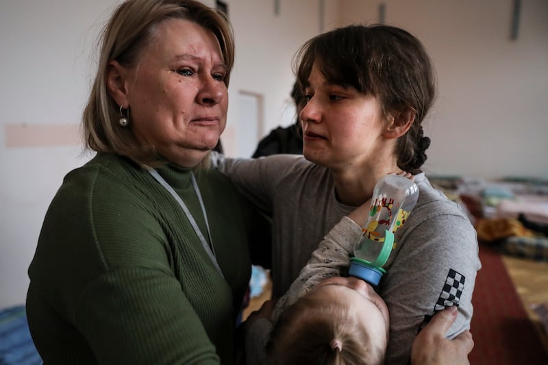 Lessa, left, director of a nursery school turned into a refugee shelter, cries as she hugs Olega, who arrived from Kyiv with her baby, near Lviv. EPA