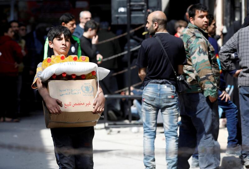 FILE PHOTO: A boy holds a cardboard box of food aid received from World Food Programme in Aleppo's Kalasa district, Syria April 10, 2019. Picture taken April 10, 2019. REUTERS/Omar Sanadiki/File Photo