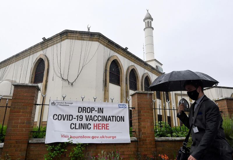 A man shields himself from rain as he walks past Hounslow Jamia Masjid and Islamic Centre, used as a vaccination clinic, amid the spread of the coronavirus disease pandemic, London, Britain. Reuters
