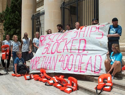Members of Lifeline's crew stage a protest outside the tribunal as Claus-Peter Reisch, the German captain of Lifeline, a private ship that rescues migrants, attends an arraignment hearing in Valletta, Malta's capital, Monday, July 2, 2018. The Lifeline rescued 234 migrants in waters off Libya, then headed to Malta after Italy refused entrance to the ship. Reisch was charged with using the boat in Maltese waters without proper registration or license. The phrase "Rescue ships blocked 400 dead" apparently referred to the many migrants who are believed to have drowned in recent days off Libya. (AP Photo/Roger Azzopardi)