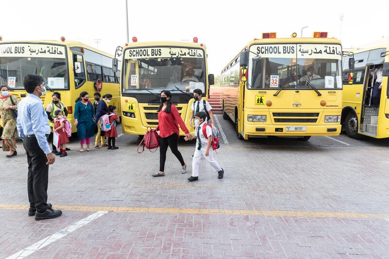 Teachers and staff members welcome pupils on their first day back at school.