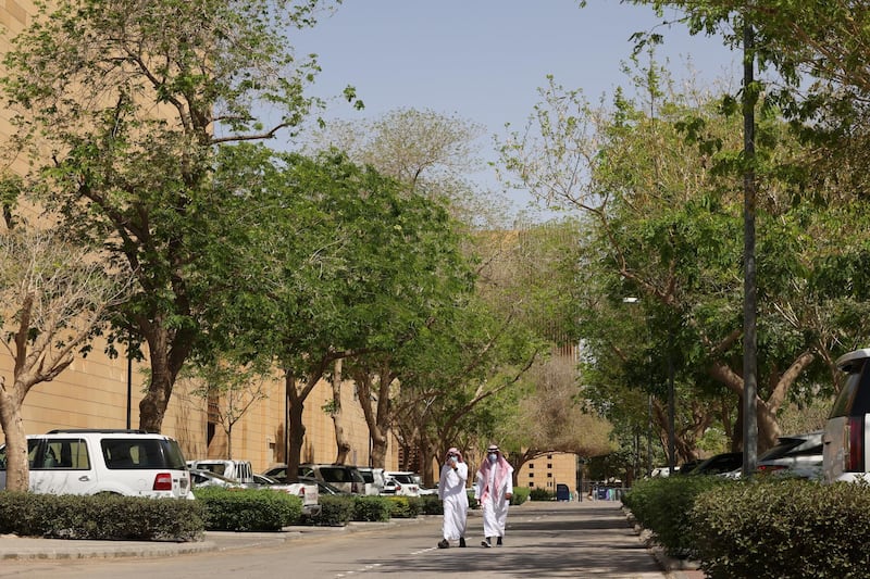 People walk on a tree-lined lane in the Saudi capital Riyadh, on March 29, 2021. - Although the OPEC kingpin seems an unlikely champion of clean energy, the "Saudi Green Initiative" aims to reduce emissions by generating half of its energy from renewables by 2030. (Photo by Fayez Nureldine / AFP)