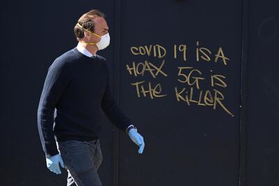 epa08362131 A man in a mask passes 5G conspiracy graffiti in London, Britain, 14 April 2020. A number of social media accounts are creating conspiracy theories about links between 5G technology and coronavirus. Countries around the world are taking increased measures to stem the widespread of the SARS-CoV-2 coronavirus which causes the Covid-19 disease.  EPA/NEIL HALL