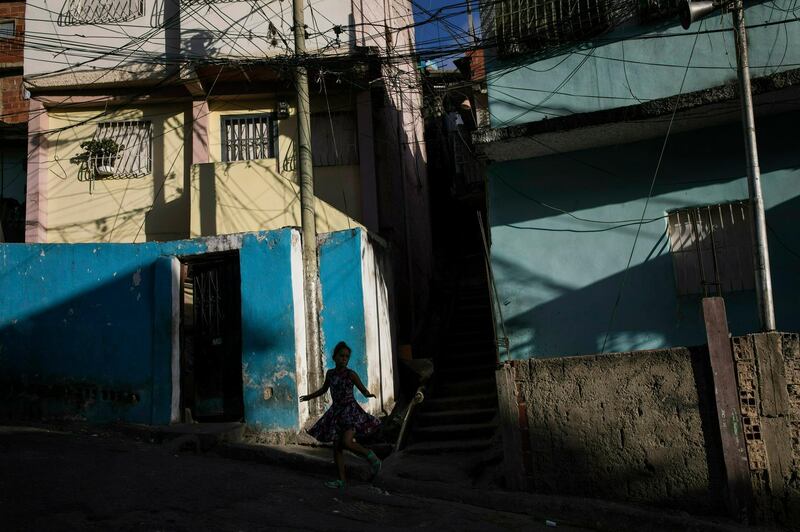 A girl runs through a neighborhood in the Petare shanty town, in Caracas, Venezuela, late Friday afternoon.  AP