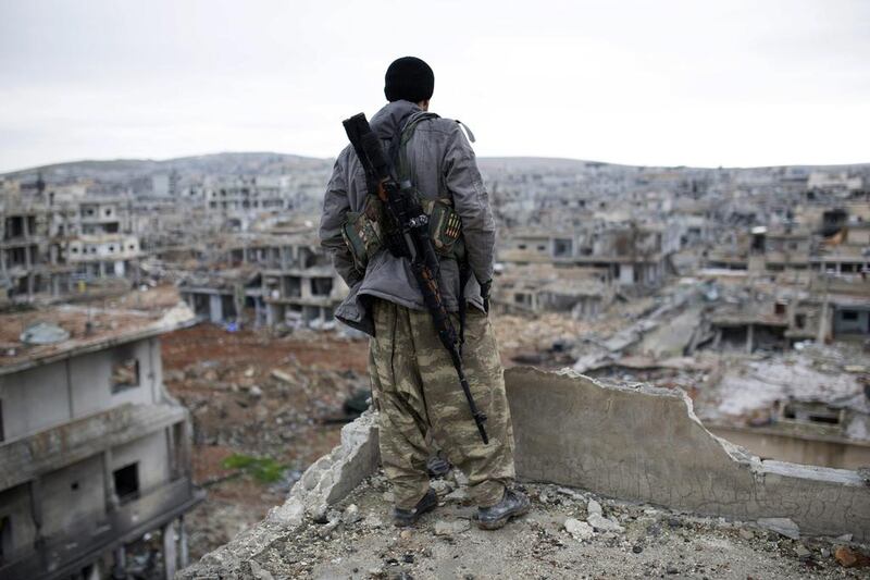 A Syrian Kurdish sniper looks at the rubble in the Syrian city of Ain al-Arab, also known as Kobane. (AP Photo, File)