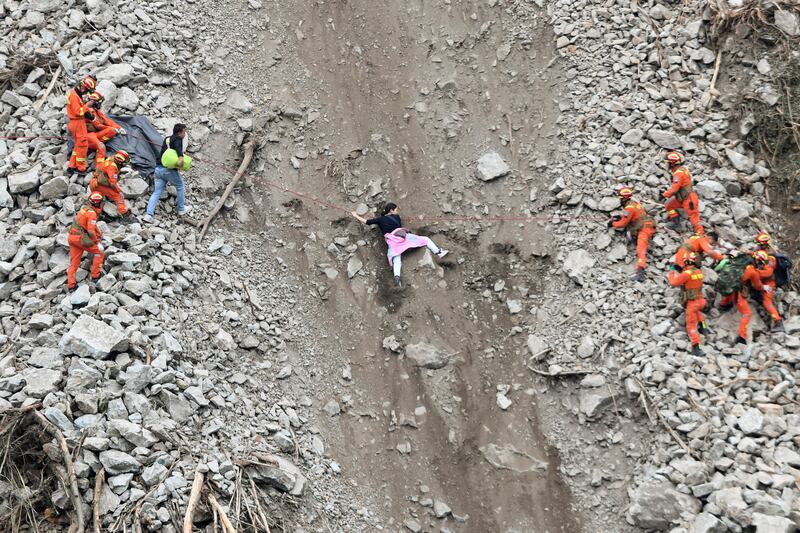 Rescue workers assist residents at the site of a landslide near the town of Moxi after a 6.8-magnitude earthquake in Sichuan province, China. Reuters