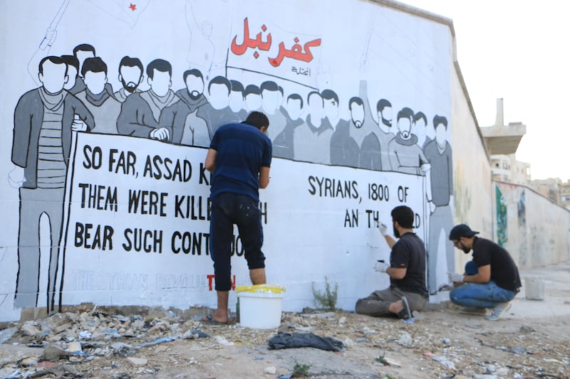 Al Shami and his friends work on a mural in Kafranbel in 2017, which points to the 1,800 victims in Syria of chemical weapons. Photo supplied by Abu Malek Al-Shami
