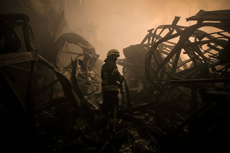 A Ukrainian firefighter drags a hose inside a large food products storage facility which was destroyed by an air strike on the outskirts of Kyiv. AP