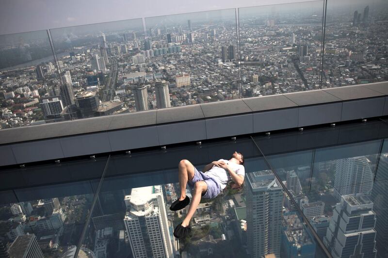 BANGKOK, THAILAND - MARCH 20:  A man lies on the glass tray at MahaNakhon Skywalk atop King Power MahaNakhon on March 20, 2019 in Bangkok, Thailand. The tower opened in November 2018 and features Thailand's tallest observatory and rooftop bar. (Photo by Brent Lewin/Getty Images)
