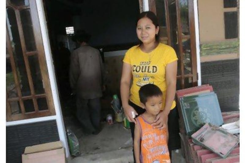 Darsem binti Dawud with her son in front of her new house in Trungtum, West Java. Tatan Syuflana / AP Photo