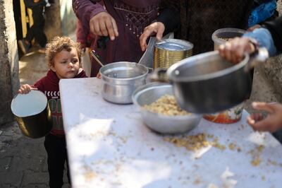 A child waits for a meal at a charity kitchen in Rafah, southern Gaza, amid growing food shortages. Reuters 