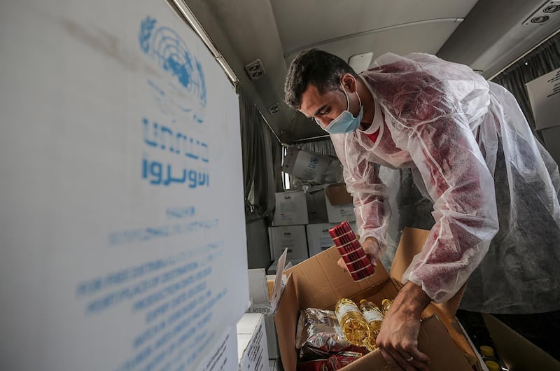 A Palestinian worker at the United Nation Relief and Works Agency (UNRWA) distributes food aid rations for refugee families, in Gaza City. EPA