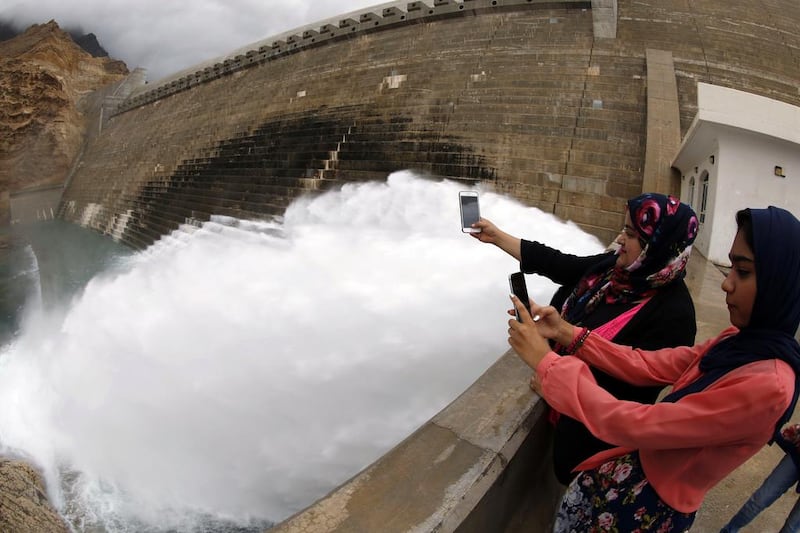 Omanis take pictures of the spillway in the Wadi Dayqah Dam, east Muscat. The sultanate was hit by heavy rains from tropical storm Ashobaa. AFP PHOTO 

