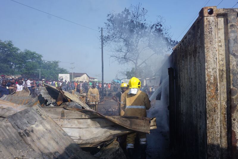 Firefighters spray water onto a burnt container at PMB Wellington Industrial Estate, east of Freetown. AFP