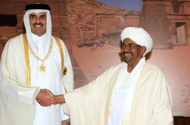 The Emir of Qatar, Sheikh Tamim bin Hamad Al Thani, left, greets the Sudanese president Omar Al Bashir during a visit to Khartoum on April 2, 2104. Ashraf Shazly / AFP