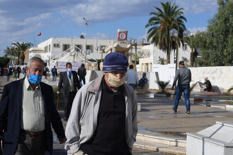 Tunisian men wearing protection masks against Covid-19 walk past the Mohamed Bouazizi's cart statue on October 27, 2020 in the central Tunisian city of Sidi Bouzid. This city, cradle of the Tunisian and Arab revolution, remains the poorest region of Tunisia. / AFP / FETHI BELAID

