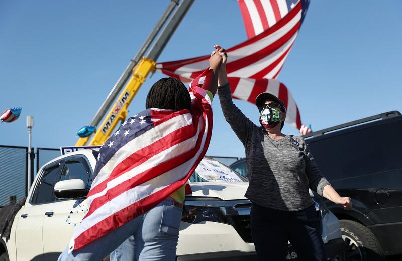 Yei Boayue and Marie Callahan celebrate the news that Joe Biden won the US presidential election at the Chase Center in Wilmington, where Mr Biden was expected to make an announcement on November 07, 2020. Getty Images / AFP