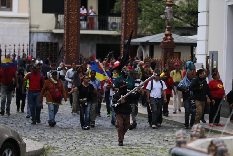 Dozens of government supporters set up a picket outside the National Assembly, heckling lawmakers during a special session coinciding with Venezuela’s independence day, in Caracas, Wednesday, July 5, 2017.  Wielding wooden sticks and metal bars the group eventually stormed congress and began attacking opposition lawmakers. (AP Photos/Fernando Llano)