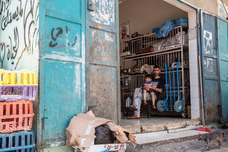 Rami Qweis waits for customers to shop in his meat store with his son in the Aida refugee camp near Bethlehem on June 23,2019.Photo by Heidi Levine for The National