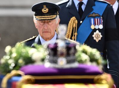 King Charles III walks behind the coffin of Queen Elizabeth II, adorned with a Royal Standard and the Imperial State Crown, during a procession from Buckingham Palace to the Palace of Westminster, in London on September 14, 2022. AFP