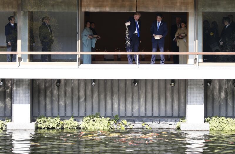 US president Donald Trump, centre, feeds carp as Shinzo Abe, Japan's prime minister, centre right, looks on at Akasaka Palace in Tokyo, Japan. Trump is on the first stop of a five-nation swing through Asia where he plans to push his message of fair trade and freedom in the region backed by a strong US military presence. Toru Hanai / Pool via Bloomberg