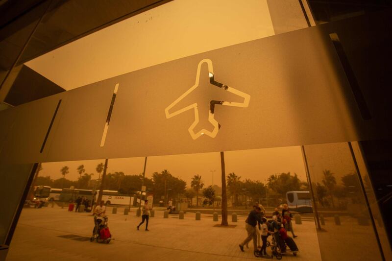 Passengers walk outside Tenerife South–Reina Sofia Airport during a sandstorm on February 23, 2020 on the Canary Island of Tenerife.  AFP