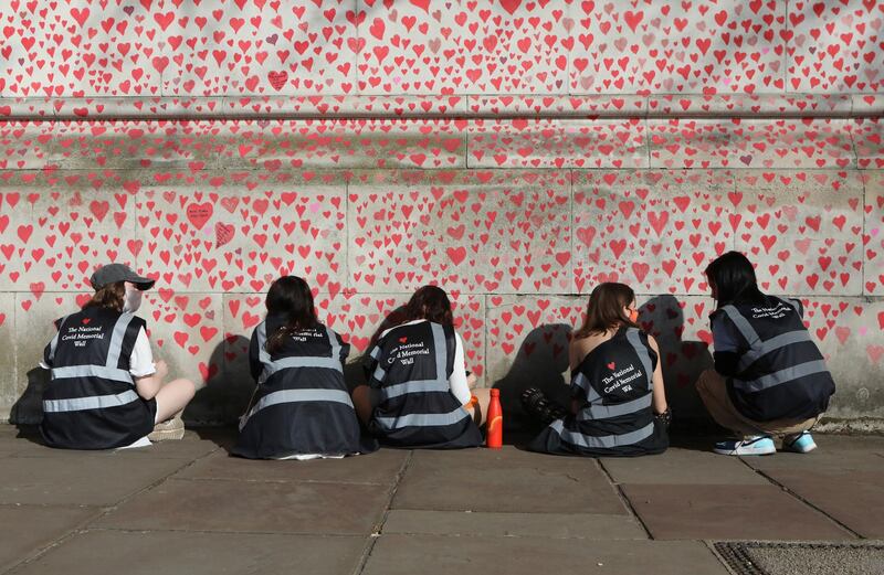 People draw hearts on the National Covid Memorial Wall on the Embankment in central London. AP Photo
