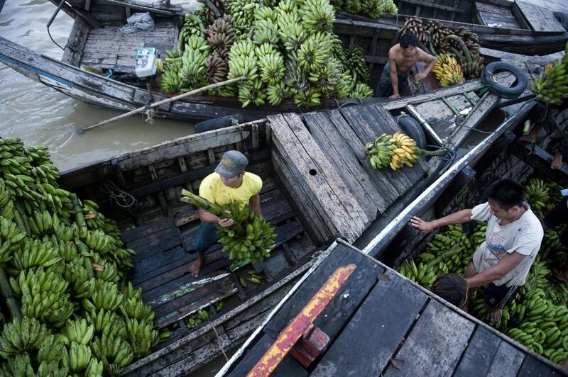 Workers unload bananas from a boat at a jetty in Yangon.  Ye Aung Thu / AFP Photo