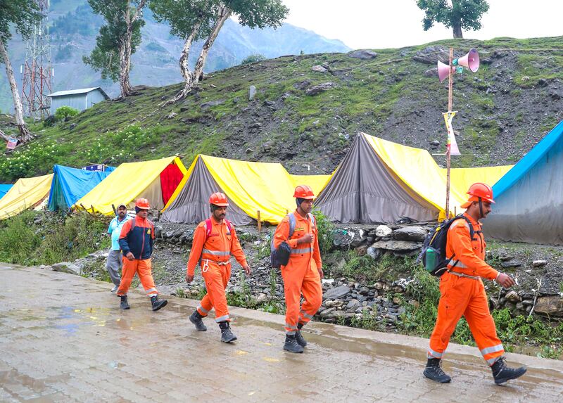 Rescuers walk towards the scene where a cloudburst hit pilgrims in Kashmir. EPA 