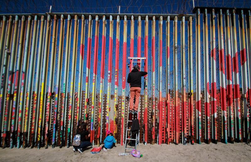 People paint the USA-Mexico border wall as part of the activity 'Wall of the Brotherhood', in Tijuana, Baja California, Mexico.  EPA