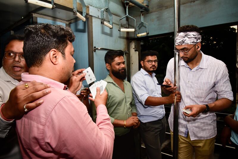 Hindu members of the group pass the time playing cards on the train as Mr Najeeb and other Muslims pray and break their fast after sunset