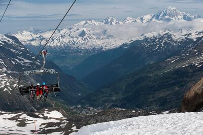 Skiers sit on a ski lift to get to the top of the skiing piste on the opening day of the summer ski season of Val D'Isere resort on June 3, 2018, in Val d'Isere, in the French Alps. - Thanks to the heavy snowfall of this winter, the ski resort of Val d'Isere has exceptionally opened in the morning of June 3, 2018, part of its ski area to offer summer skiing, which is usually done on a glacier. (Photo by ROMAIN LAFABREGUE / AFP)