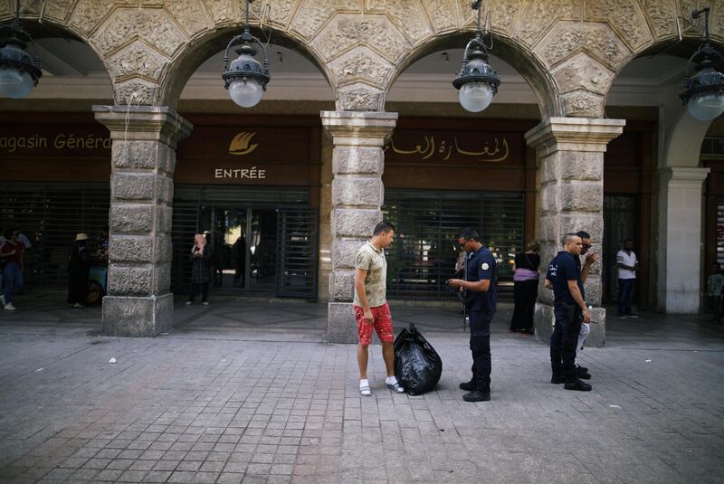 Police officers search the belongings of a civilian in Tunis, Tunisia.  Reuters