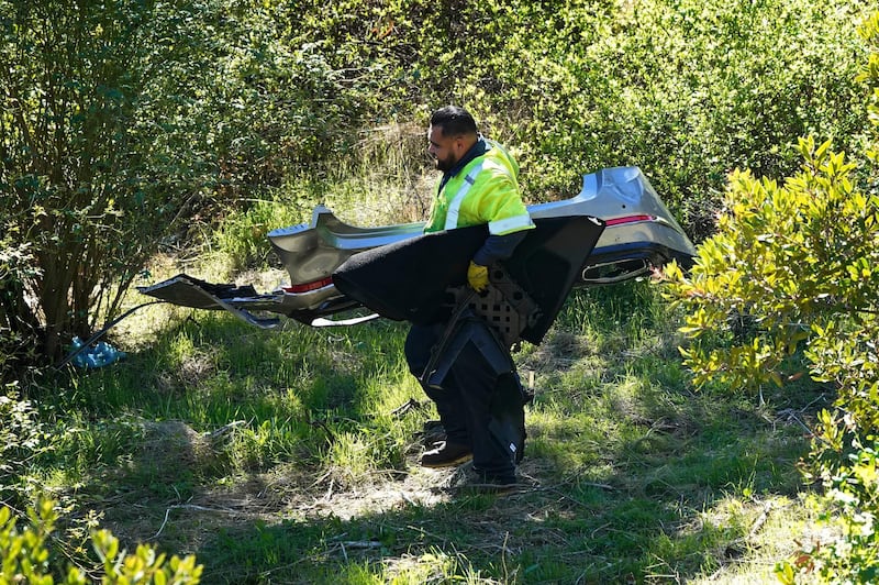 A worker moves debris after a rollover accident involving golfer Tiger Woods. AP Photo