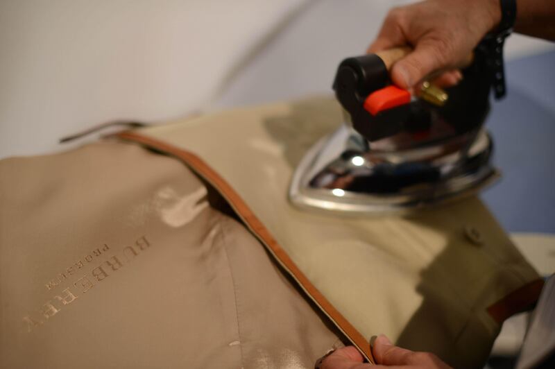 A taylor irons a garment backstage ahead of the Burberry Prorsum 2013 spring/summer collection catwalk show during London Fashion Week in London on September 17, 2012. AFP PHOTO / BEN STANSALL