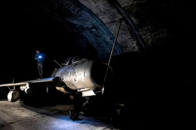 An Albanian military officer inspects a MIG-19 jet fighter inside the main tunnel of the Gjader Air Base built near the city of Lezhe, on February 5, 2019. On a barren hillside in northern Albania lies a portal to the country's communist past: a massive steel door creaks open to reveal a hidden former air base burrowed into the heart of the mountain. Made up of 600 metres (1,980 feet) of tunnels that once teemed with military life, the secret Gjader air base is now a depot for dozens of hulking communist-era MiG jets collecting dust in the darkness. Three decades after shedding communism, Albanian authorities are still trying to sell off the Soviet and Chinese-made aircraft, of which there are dozens more in another nearby air base.
 / AFP / Gent SHKULLAKU
