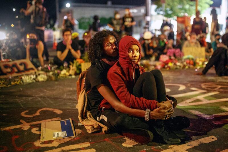 A Somali-American couple, alongside protesters calling for justice for the death of George Floyd, waits after curfew outside the Cup Foods in Minneapolis, Minnesota.   AFP