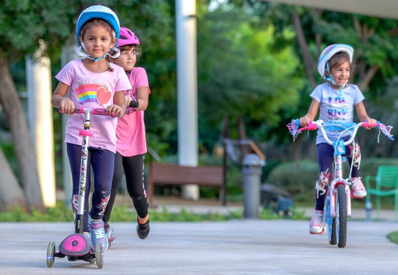Abu Dhabi, United Arab Emirates, October 26, 2020.  The "new norm" of Covid-19 precautionary measures at Umm Al Emarat Park, Abu Dhabi, on a Monday afternoon.  Best of friends, (left) Layan Abuchaker, 4, Talia Abuchaker, 6 and Tuleen Alhanjol, 6, ride their scooters and bike around the park.
Victor Besa/The National
Section:  NA
Reporter: