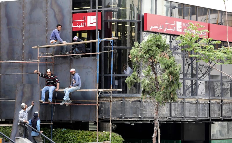 Workers install metallic barriers along the facade of a bank as a protective measure against vandalism in the Lebanese capital Beirut.   AFP