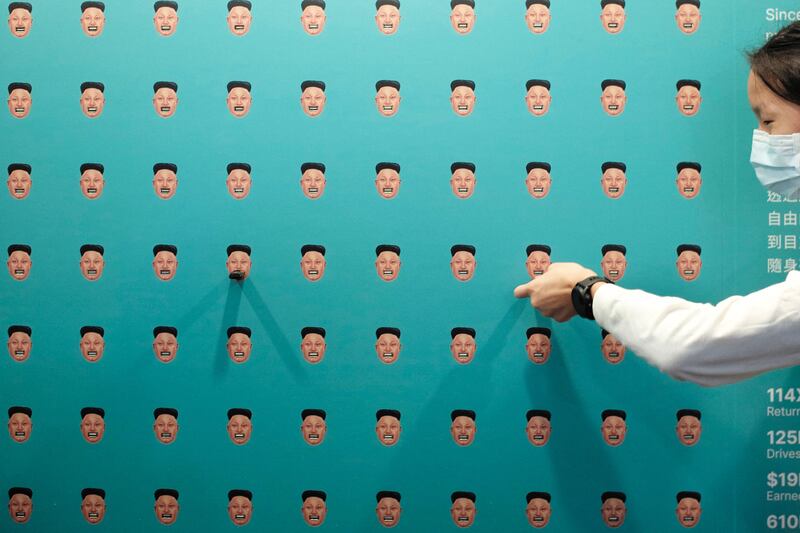 A woman plugs a USB media device containing freedom-related content into a socket on a wall depicting multiple heads of North Korean leader Kim Jong Un during the Oslo Freedom Forum in Taipei. AFP