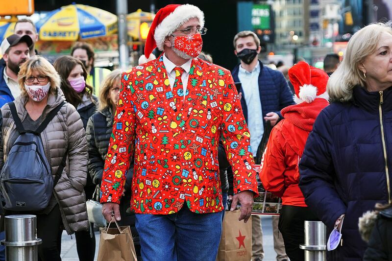 A man wearing a festive jacket, tie and matching mask walks through Times Square in New York. Reuters