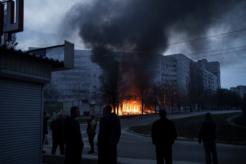 Residents stand outside their apartments as shops burn after a Russian attack in Kharkiv, Ukraine. AP