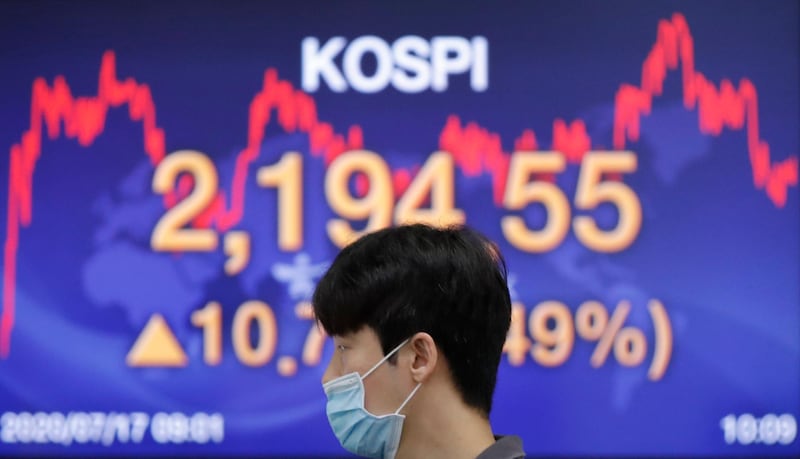 A currency trader wearing a face mask walks by the screen showing the Korea Composite Stock Price Index (KOSPI) at the foreign exchange dealing room in Seoul, South Korea, Friday, July 17, 2020. Asian stock markets rebounded Friday after Wall Street closed lower amid uncertainty about the U.S. economic outlook. (AP Photo/Lee Jin-man)