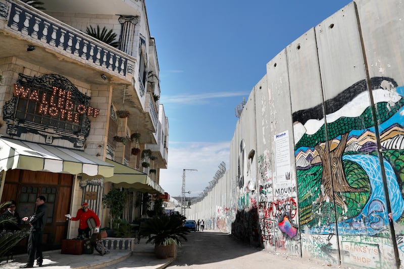 The Israeli controversial separation wall is seen in front of artist Banksy's newly opened Walled Off hotel in the Israeli occupied West Bank town of Bethlehem, on March 15, 2017. 
Secretive British street artist Banksy opened a hotel next to Israel’s controversial separation wall in Bethlehem on Friday, his latest artwork in the Palestinian territories. / AFP PHOTO / THOMAS COEX
