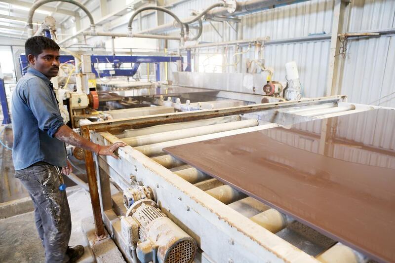 A worker checks one of the larger ceramic tiles. RAK Ceramics ships these to more than 160 countries around the world. Pawan Singh / The National
