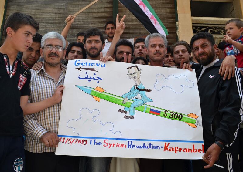 Demonstrators pose with a placard depicting Syrian President Bashar Al Assad riding a Russian S-300 missile heading to Geneva, in reference to the Syrian arms agreement with Russia and the upcoming Geneva convention on May 31, 2013 . AFP