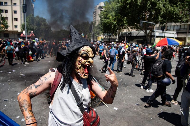 A demonstrator wearing a witch mask commemorates the first anniversary of the social uprising in Chile, in Santiago as the country prepares for a landmark referendum.  AFP